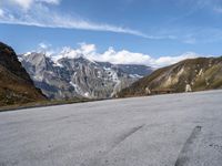 an empty tarmac on the top of a mountain road with snow capped mountains in the background