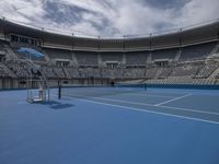 the court is empty at a stadium with many empty seats and a blue court is also seen