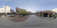 an 360 - degree view of an empty town street with shops and buildings, as seen through the fisheye lens