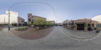 an 360 - degree view of an empty town street with shops and buildings, as seen through the fisheye lens