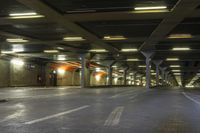 an empty train station with lights lit up in the dark time, under a concrete covered ceiling