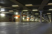 an empty train station with lights lit up in the dark time, under a concrete covered ceiling