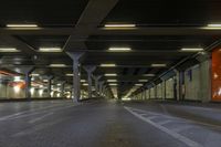 an empty train station with lights lit up in the dark time, under a concrete covered ceiling