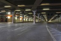 an empty train station with lights lit up in the dark time, under a concrete covered ceiling