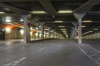 an empty train station with lights lit up in the dark time, under a concrete covered ceiling