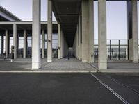 empty train station with a person standing on the platform, walkways and buildings behind it