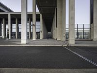 empty train station with a person standing on the platform, walkways and buildings behind it