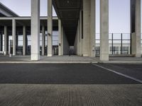 empty train station with a person standing on the platform, walkways and buildings behind it