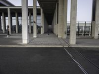 empty train station with a person standing on the platform, walkways and buildings behind it