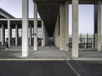 empty train station with a person standing on the platform, walkways and buildings behind it