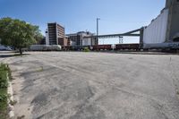 the empty lot of a train yard has two trains in it and an overpass with tracks