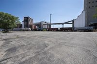 the empty lot of a train yard has two trains in it and an overpass with tracks
