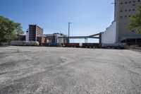 the empty lot of a train yard has two trains in it and an overpass with tracks