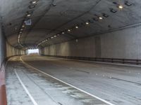 a empty tunnel is next to a roadway with white lines on it and people walking