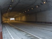 a empty tunnel is next to a roadway with white lines on it and people walking