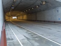 a empty tunnel is next to a roadway with white lines on it and people walking