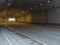 a empty tunnel is next to a roadway with white lines on it and people walking