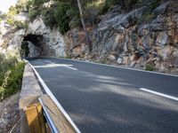 a tunnel in the middle of the mountain next to the road is empty but there is no traffic