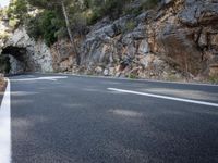 a tunnel in the middle of the mountain next to the road is empty but there is no traffic