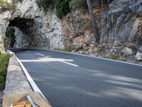 a tunnel in the middle of the mountain next to the road is empty but there is no traffic