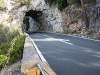 a tunnel in the middle of the mountain next to the road is empty but there is no traffic