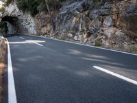 a tunnel in the middle of the mountain next to the road is empty but there is no traffic
