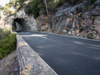 a tunnel in the middle of the mountain next to the road is empty but there is no traffic
