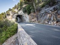 a tunnel in the middle of the mountain next to the road is empty but there is no traffic