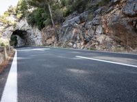 a tunnel in the middle of the mountain next to the road is empty but there is no traffic