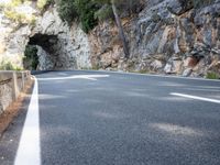 a tunnel in the middle of the mountain next to the road is empty but there is no traffic