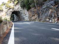 a tunnel in the middle of the mountain next to the road is empty but there is no traffic