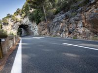 a tunnel in the middle of the mountain next to the road is empty but there is no traffic