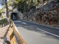 a tunnel in the middle of the mountain next to the road is empty but there is no traffic