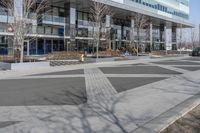 an empty area near buildings is shown with trees in the foreground, and several pedestrians walk on the pavement