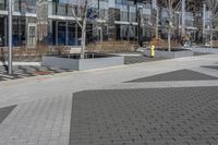 an empty area near buildings is shown with trees in the foreground, and several pedestrians walk on the pavement