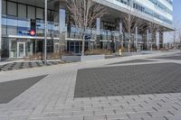 an empty area near buildings is shown with trees in the foreground, and several pedestrians walk on the pavement