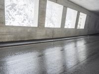 an empty urban road in the rain under a covered bridge of windows and concrete walls