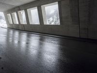 an empty urban road in the rain under a covered bridge of windows and concrete walls