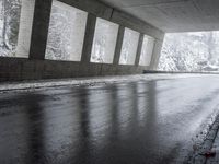 an empty urban road in the rain under a covered bridge of windows and concrete walls