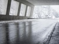 an empty urban road in the rain under a covered bridge of windows and concrete walls