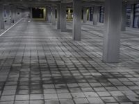 this empty indoor space features brick flooring and large windows that overlook over an urban area