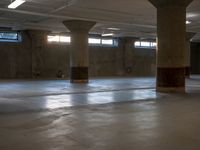 an empty concrete warehouse with sunlight shining through the windows and cement pillars in the ceiling