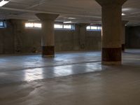 an empty concrete warehouse with sunlight shining through the windows and cement pillars in the ceiling