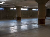 an empty concrete warehouse with sunlight shining through the windows and cement pillars in the ceiling