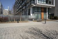 there is an empty walkway with a bench beside it in the background that also has an apartment building