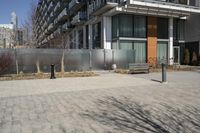 there is an empty walkway with a bench beside it in the background that also has an apartment building