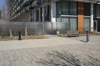 there is an empty walkway with a bench beside it in the background that also has an apartment building