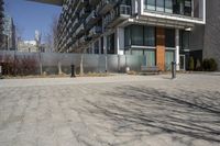 there is an empty walkway with a bench beside it in the background that also has an apartment building