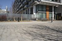 there is an empty walkway with a bench beside it in the background that also has an apartment building