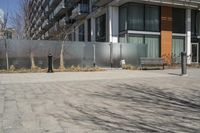 there is an empty walkway with a bench beside it in the background that also has an apartment building